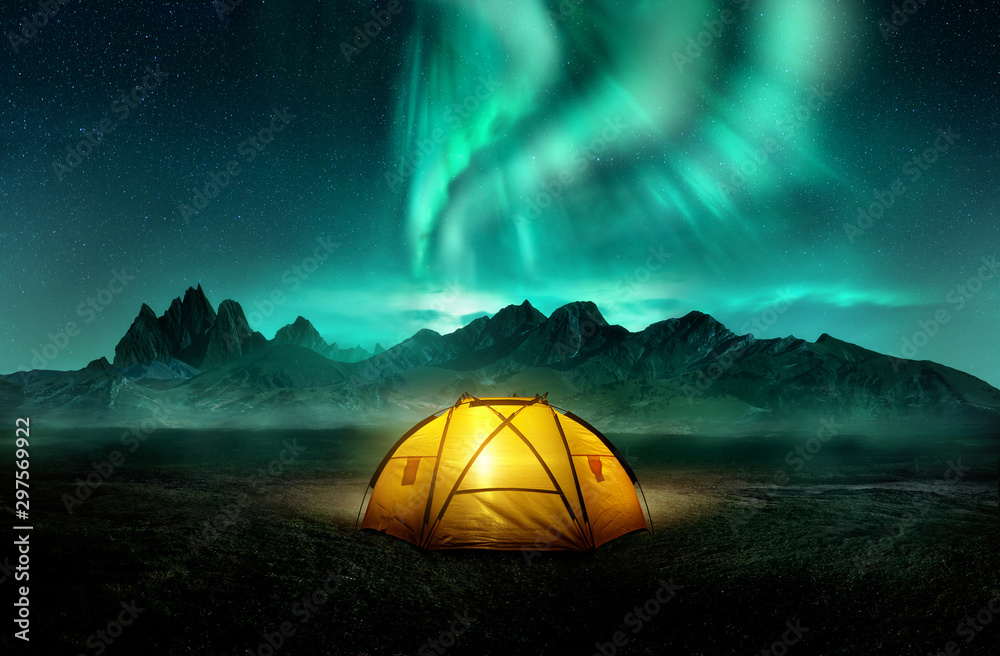 美丽的绿色北极光下，一个发光的黄色露营帐篷。旅行冒险之地