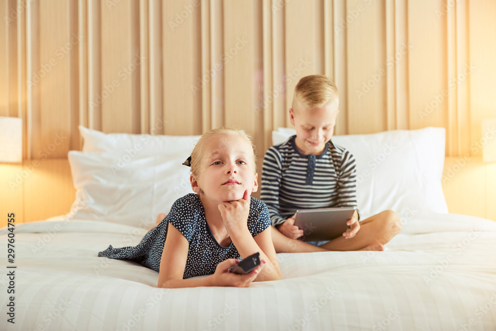 Little girl watching tv on a bed with her brother