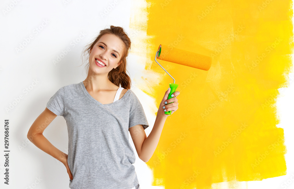 公寓维修。快乐的年轻女人粉刷墙壁