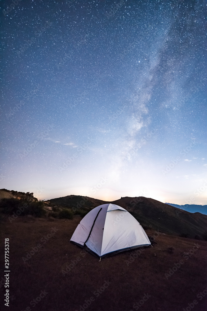 徒步旅行者夜晚在山上搭帐篷，天空中有星星