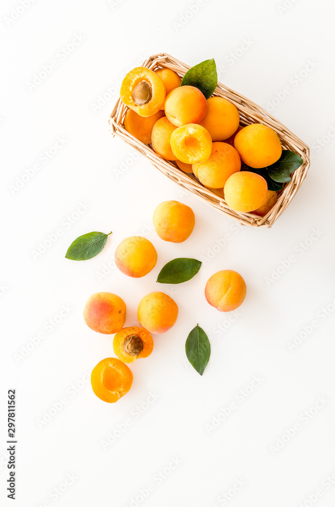 白色背景篮子里的新鲜生杏子俯视图复制空间，带叶子的图案