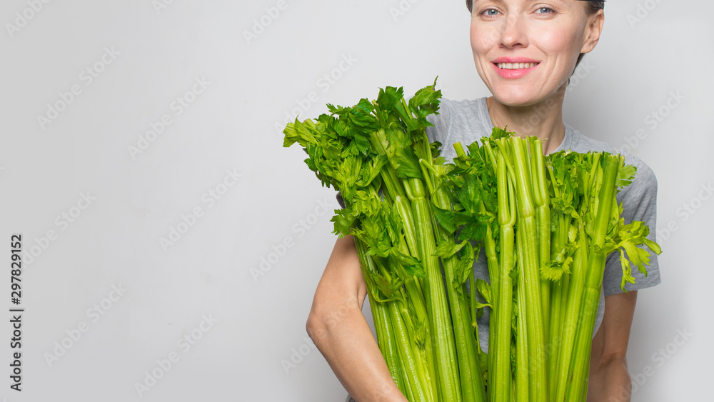 拿着绿色新鲜芹菜的女人。健康饮食、素食、节食和以人为本