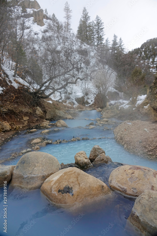 垂直：美丽的浅蓝色泉水从一个池塘倾泻到另一个池塘