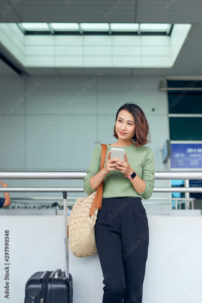 一名亚洲女子在亚洲机场等待时正在检查她的智能手机。