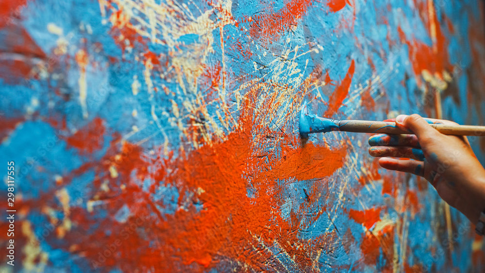 女艺术家手拿画笔用红漆作画的特写镜头。Colorf