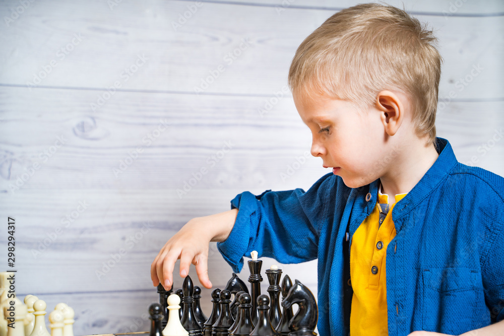 男孩在下棋。可爱的小孩在玩逻辑和大脑发育的棋盘游戏。