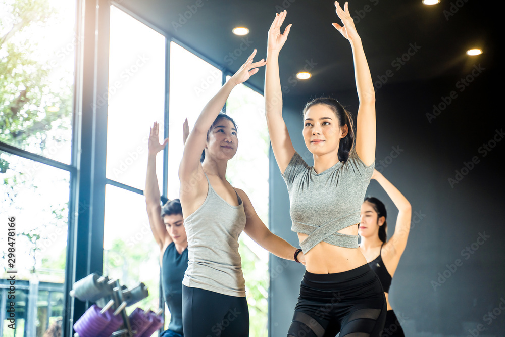 一群多元化的人在瑜伽课上训练瑜伽。亚洲年轻的女教练教女孩做瑜伽