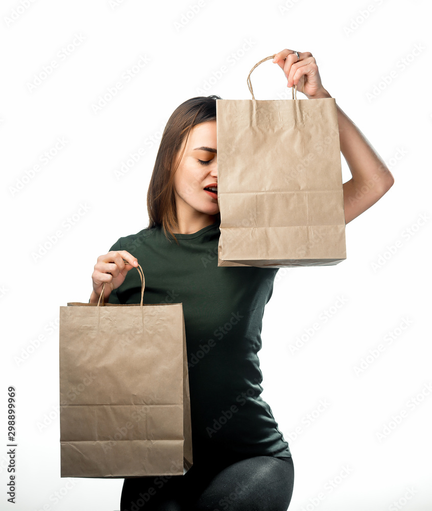 一名女子拿着两个白色背景的杂货购物袋。纸袋靠近面部。背部孤立。