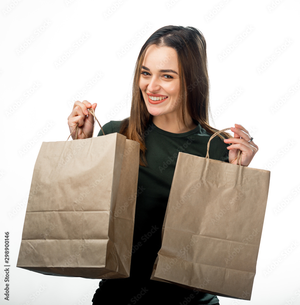一个漂亮的女孩手里拿着两个白色背景的杂货购物袋。浅棕色纸袋