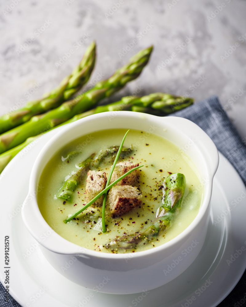 Green asparagus soup with crackers in white bowl closeup. Food photography