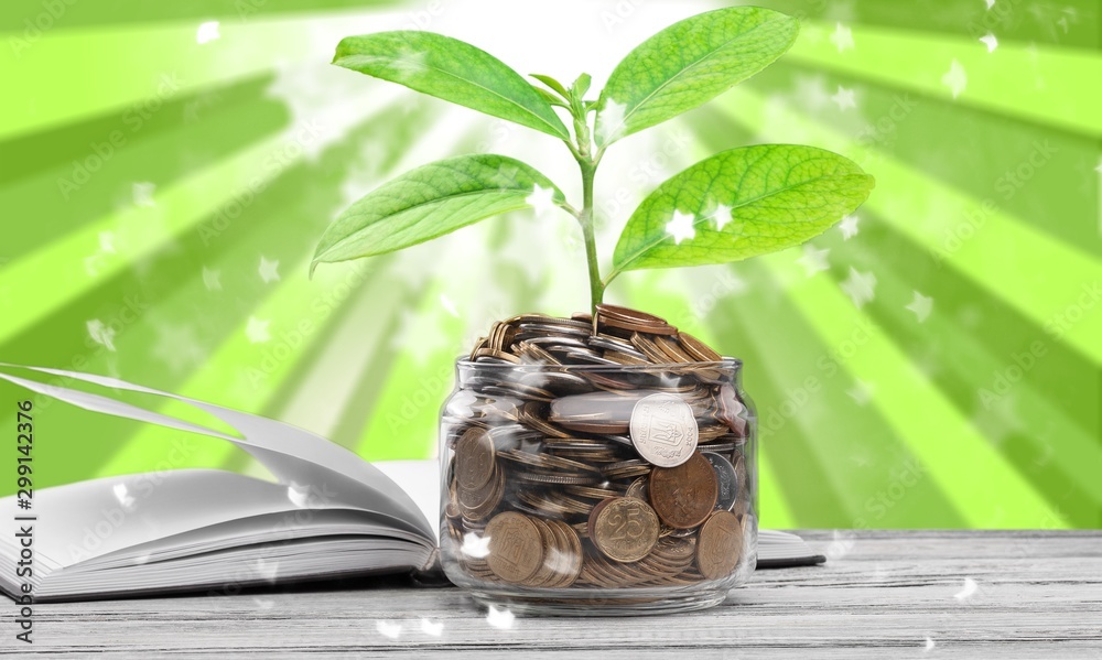 金融教育理念，装硬币和绿芽的罐子，桌子上的开卷