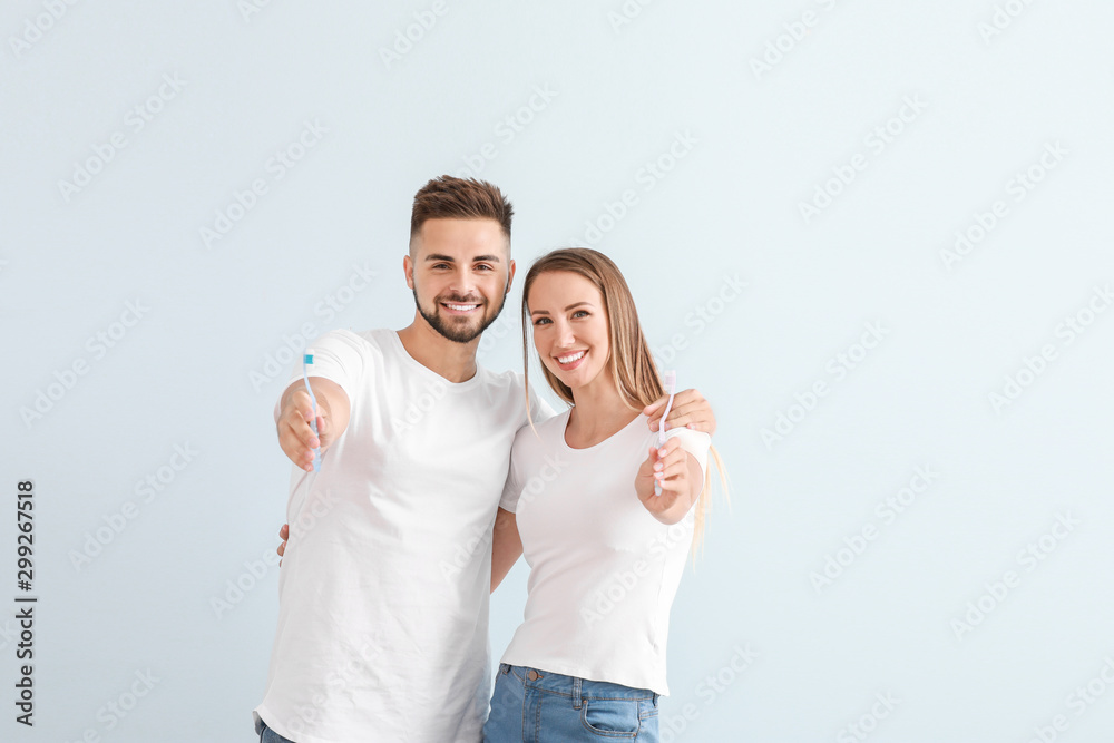 浅色背景下一对年轻夫妇拿着牙刷的肖像