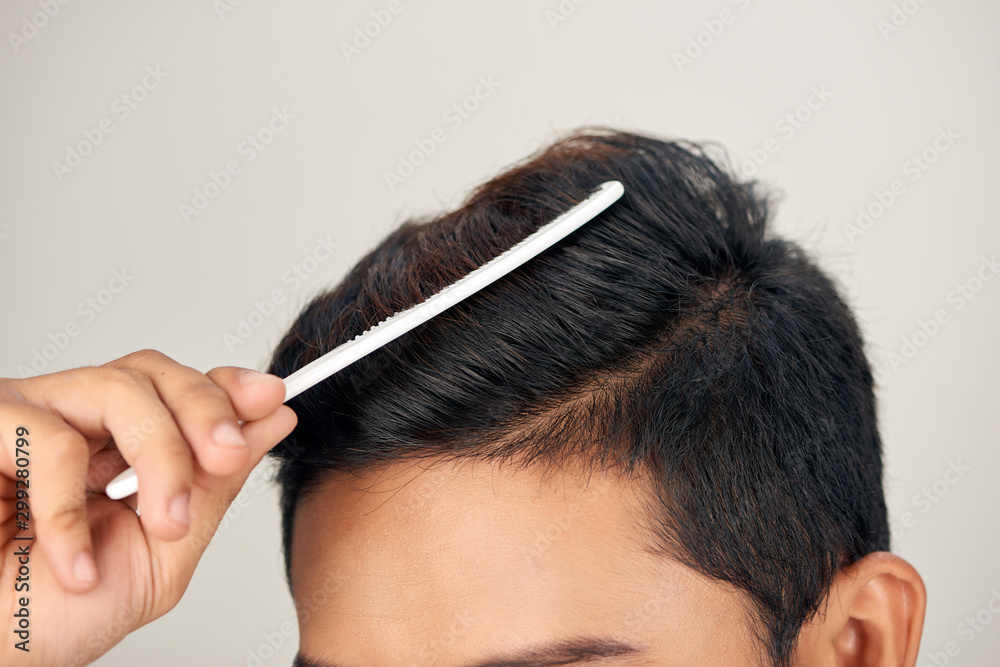 健康男人头发的特写照片。年轻人梳头