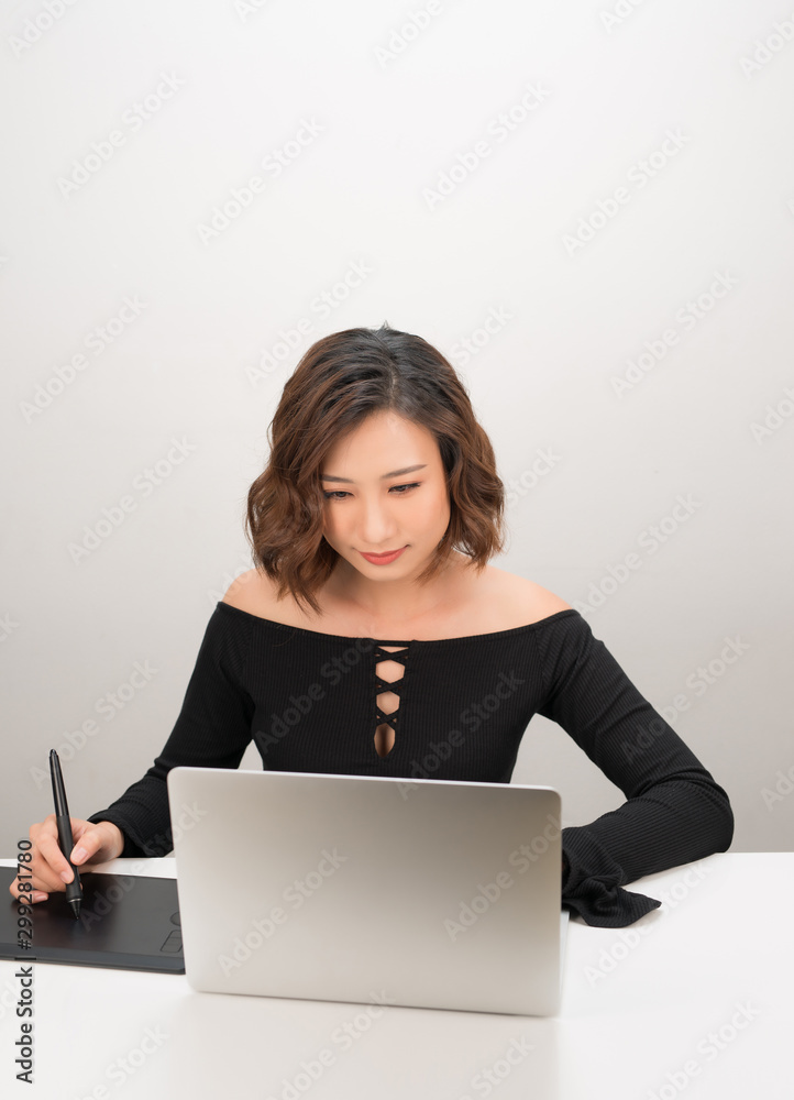 年轻的亚洲女设计师在使用电脑时使用图形平板电脑