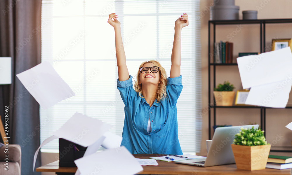 年轻快乐的商业女性在电脑上工作，并在办公室里扔文件