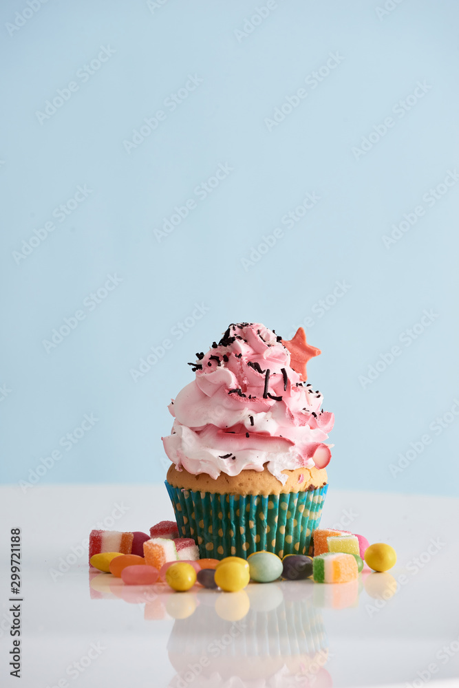 桌上有糖果的粉红色奶油糖霜纸杯蛋糕