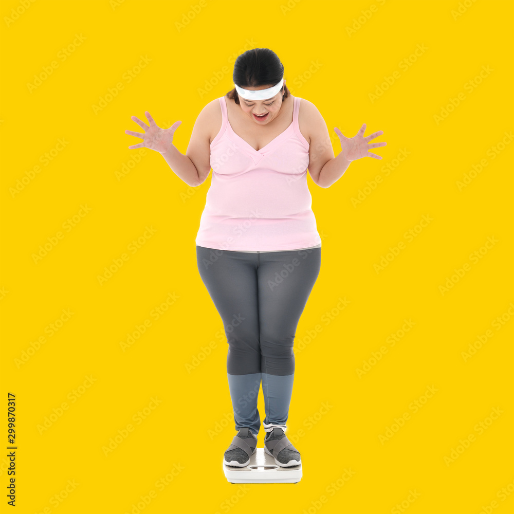 超重的亚洲女性看到体重秤上的体重看起来很震惊