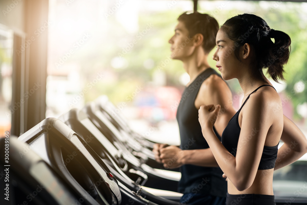 年轻的白人男性和亚裔女性的两个朋友在健身房锻炼和锻炼。他们慢跑