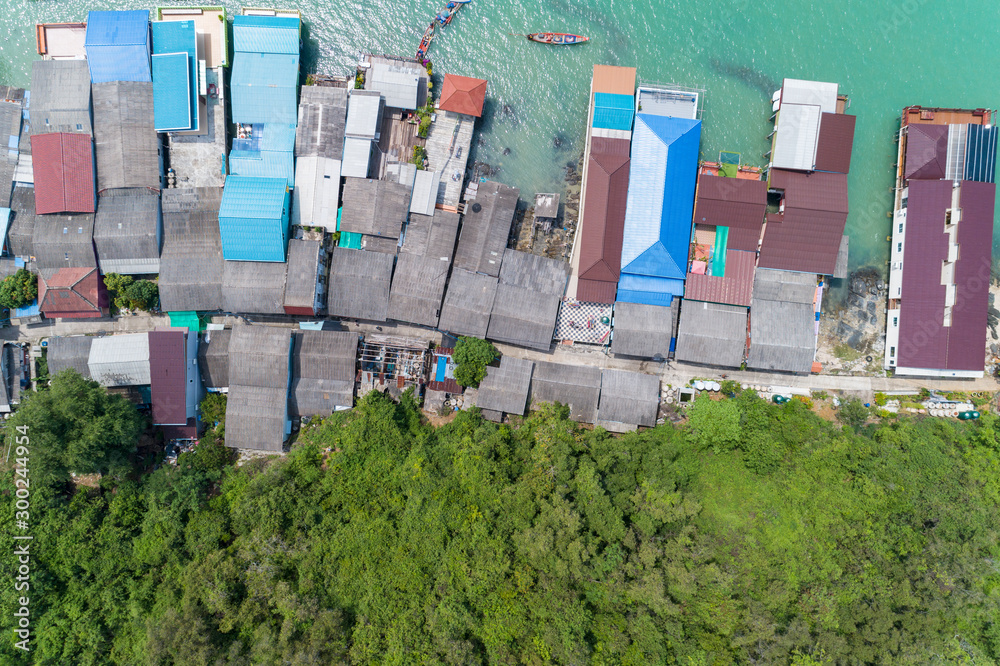 Aerial view top view of the fisherman village with fishing boats and house’s roof at the pier in koh