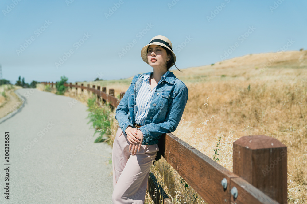 优雅的亚洲韩国女游客戴着草帽，倚在户外欣赏美丽的自然风光