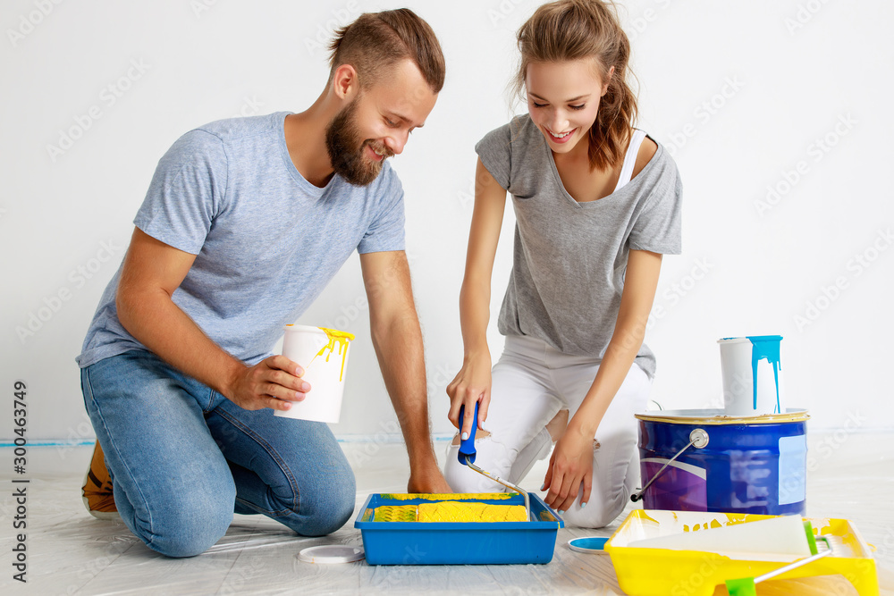 年轻幸福的一对夫妇正在家里修理和粉刷墙壁