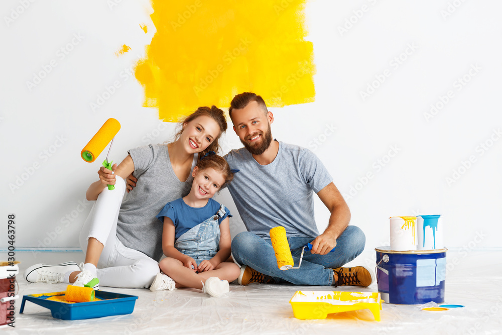 Repair in apartment. Happy family mother, father and child daughter  paints wall