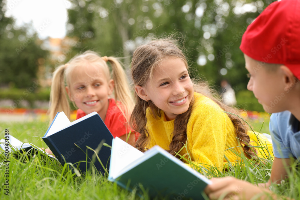 一群小孩子在公园的绿草上看书