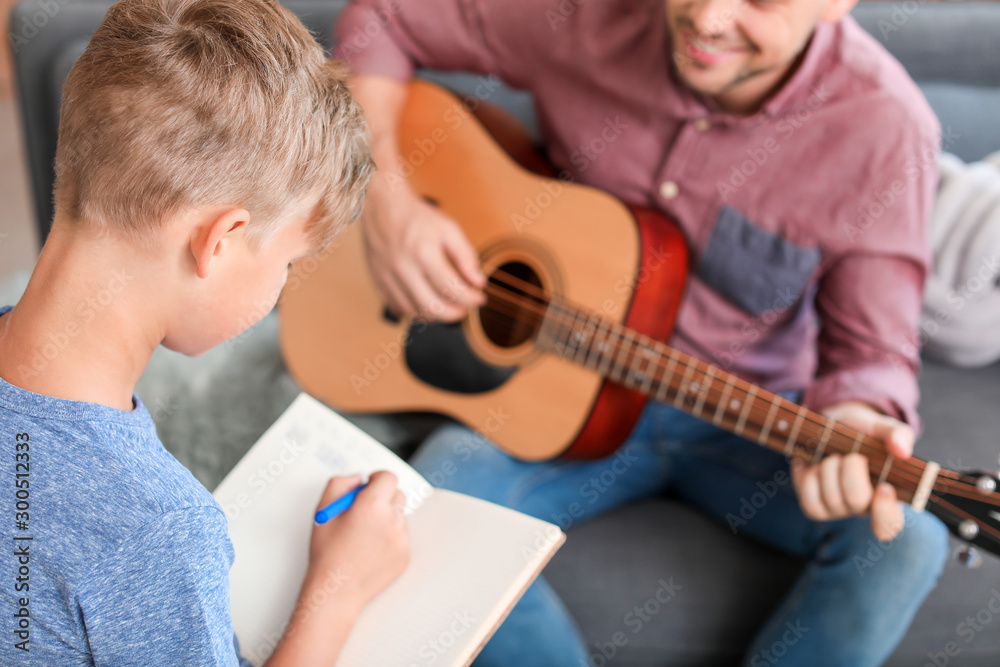小男孩和他的父亲在家弹吉他