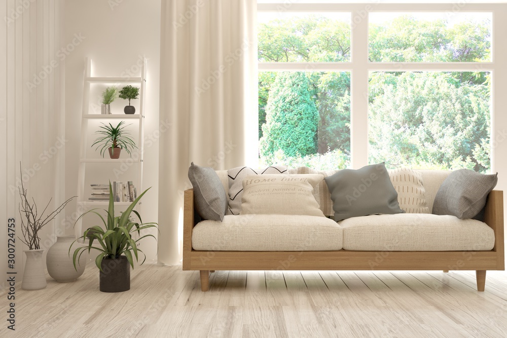 时尚的白色房间，窗户里有沙发和夏季景观。斯堪的纳维亚室内设计。