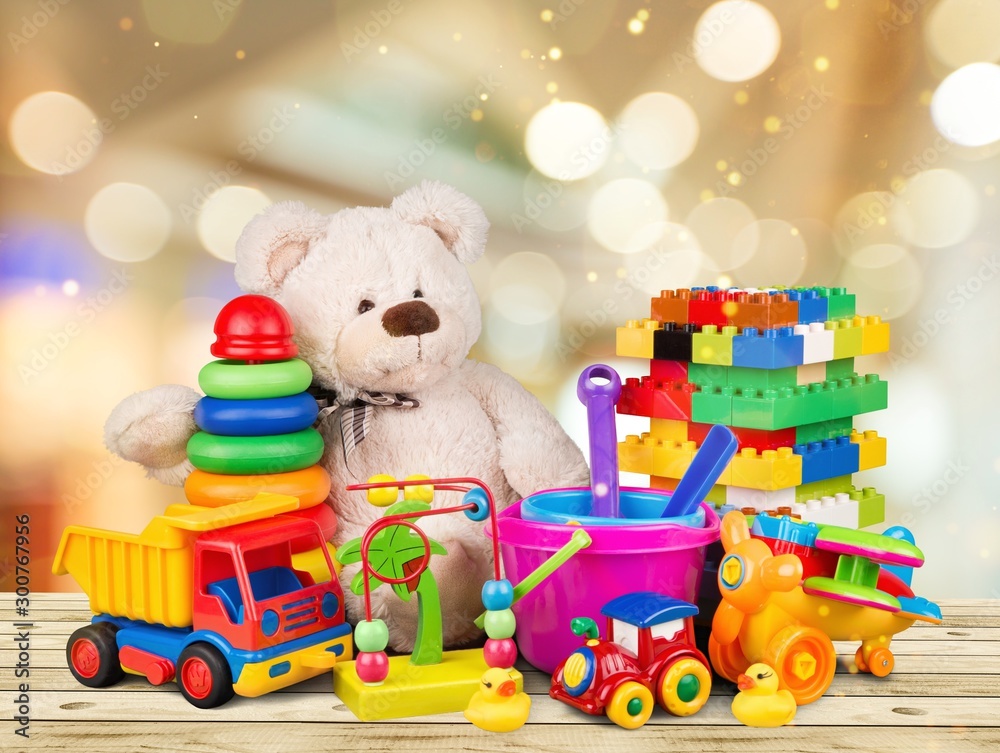 抽象灯光背景下木桌上的熊和五颜六色的玩具