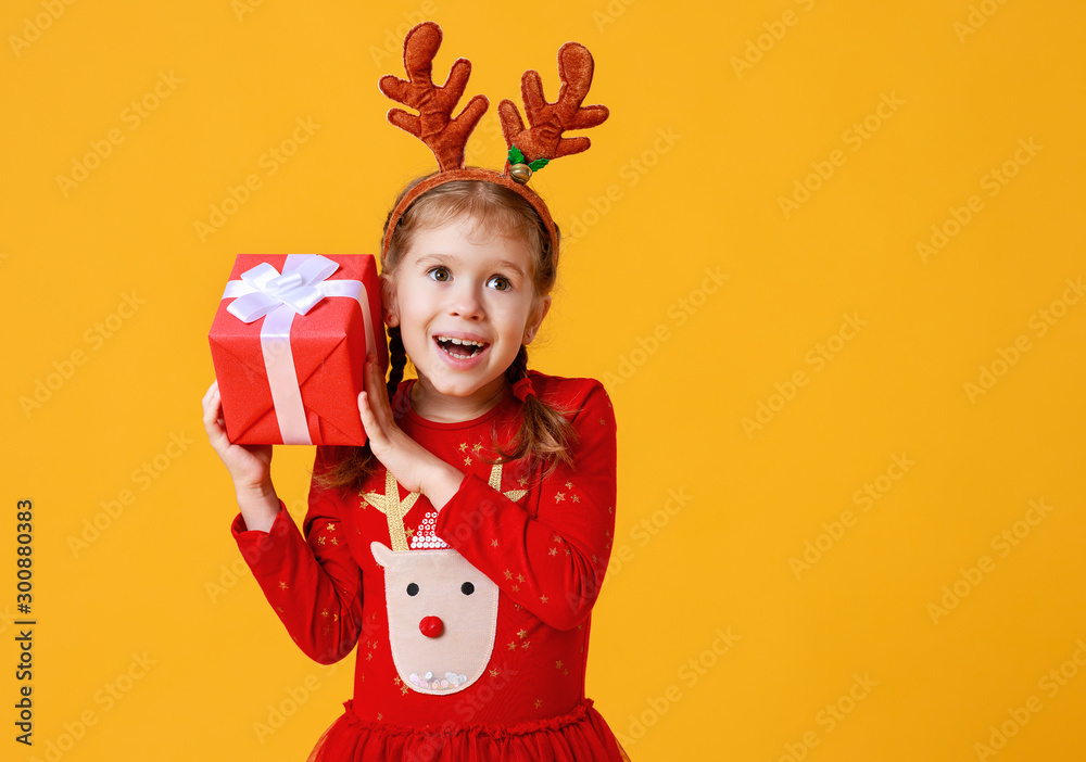 快乐有趣的小女孩，穿着红色圣诞驯鹿服装，黄底礼物