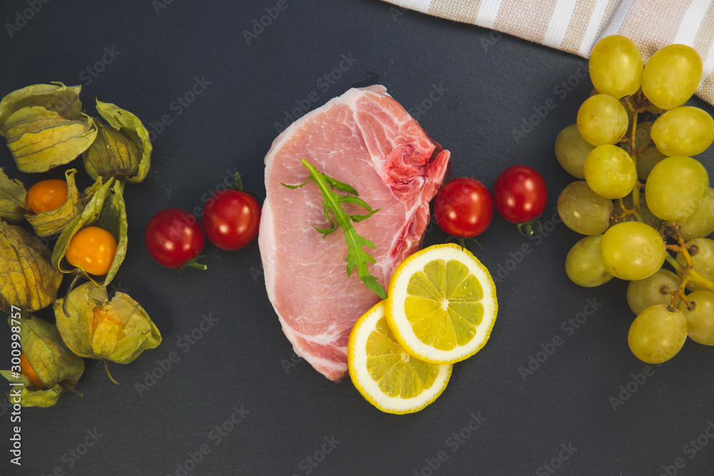  Fresh pork steak with lemon,grapes,tomatoes on Stone tray view.
