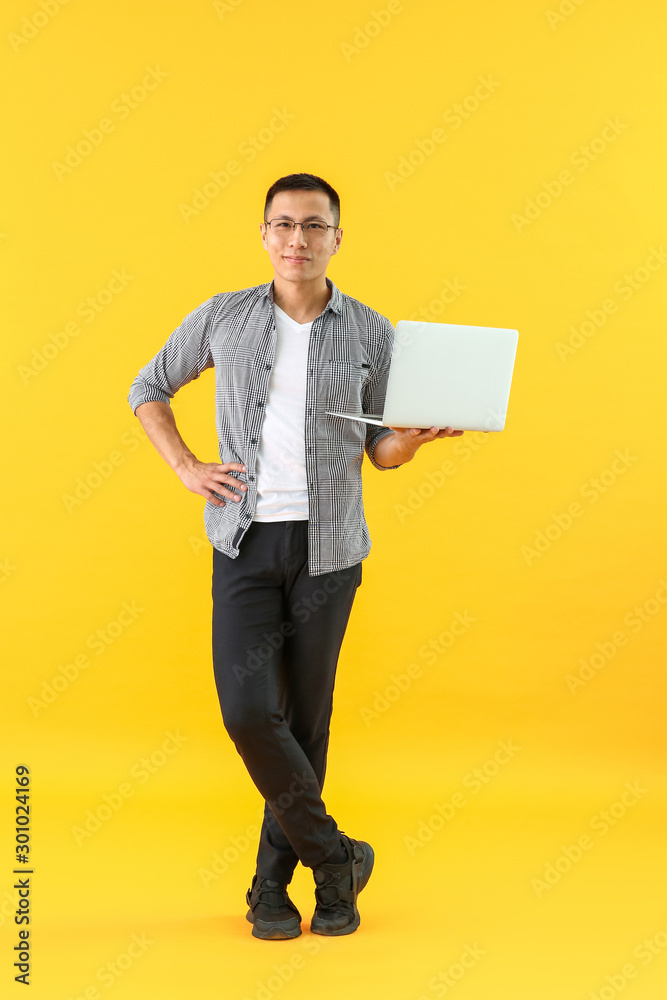 亚洲男程序员，彩色背景笔记本电脑