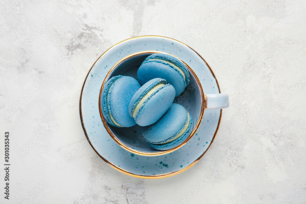 Cup with tasty macarons on white background