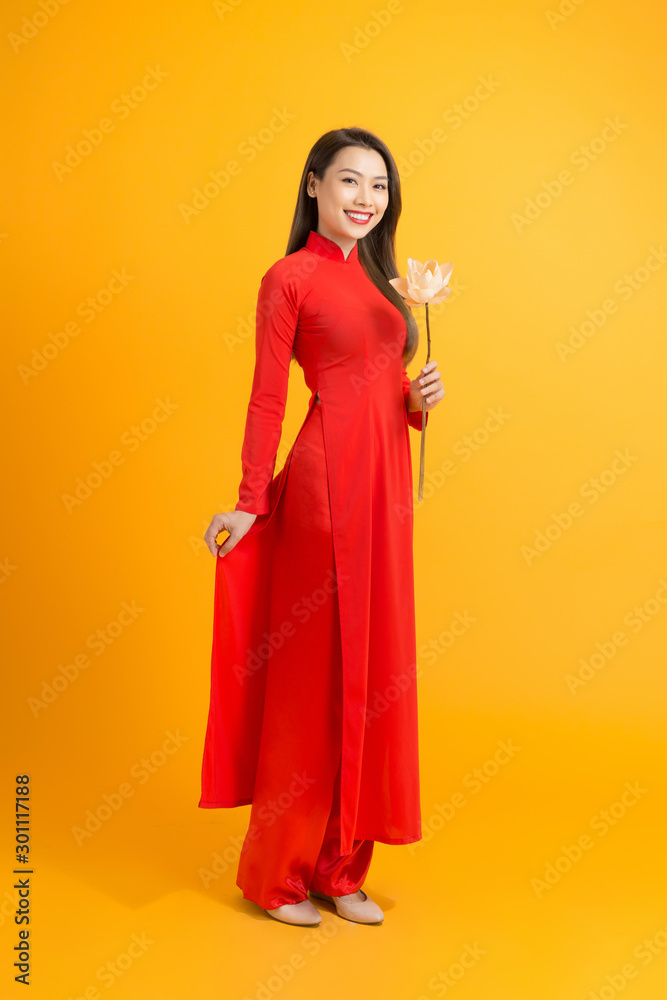 Beautiful girl wearing traditional Vietnamese dress hand holding pink flowers.