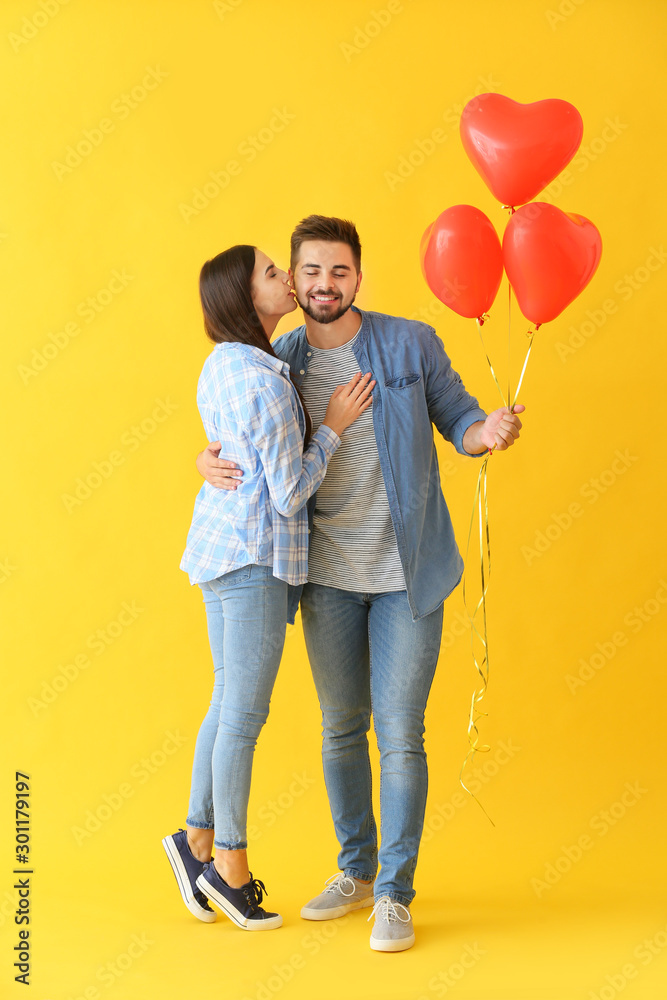 Portrait of beautiful young couple with air balloons on color background