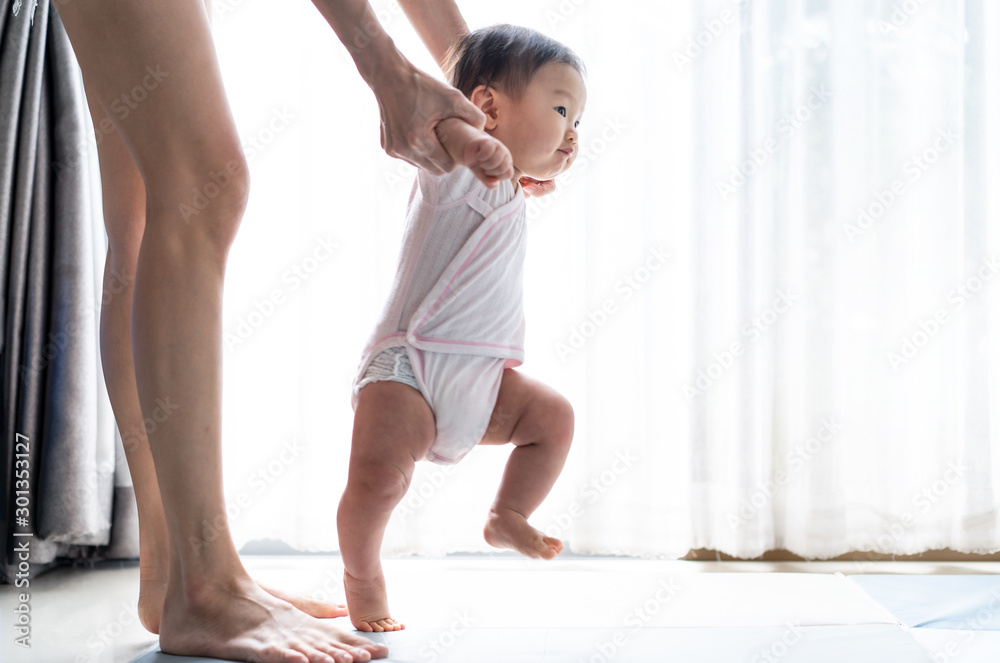亚洲宝宝迈出第一步，在柔软的垫子上向前走。快乐的小宝宝一起学习走路