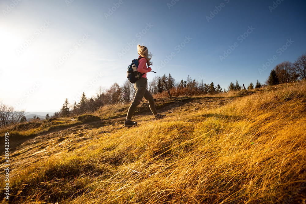 背着背包徒步旅行的年轻女子在群山景观背景下登上山顶