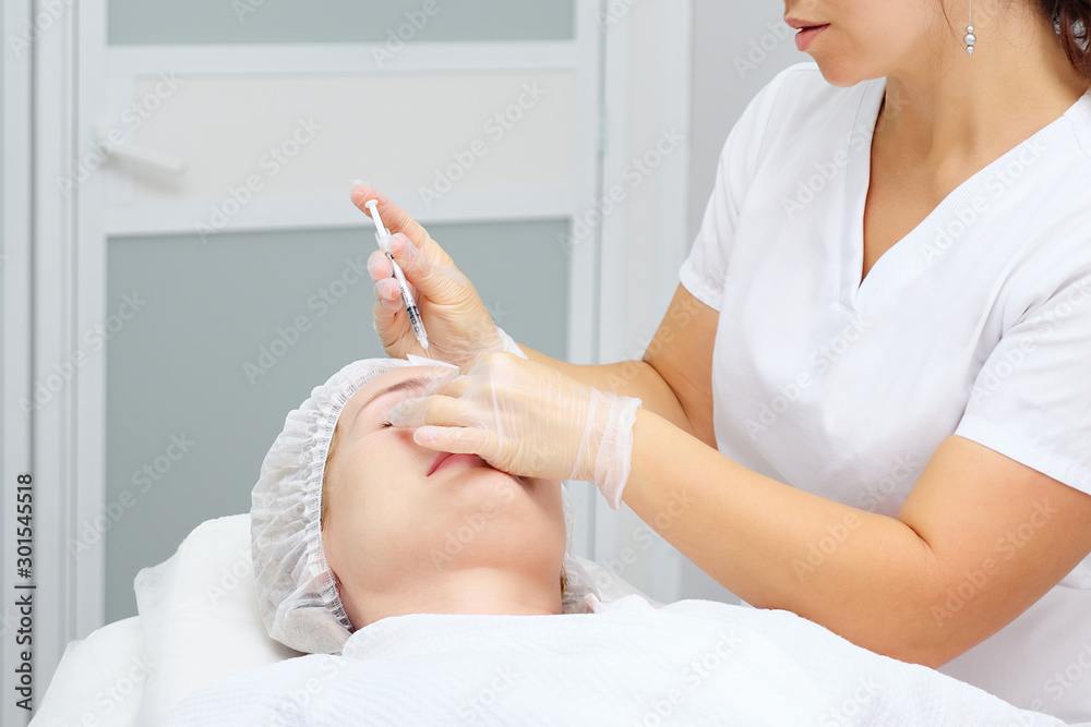 美容师使用胶原蛋白填充物进行医疗手术，抚平女性额头上的皱纹