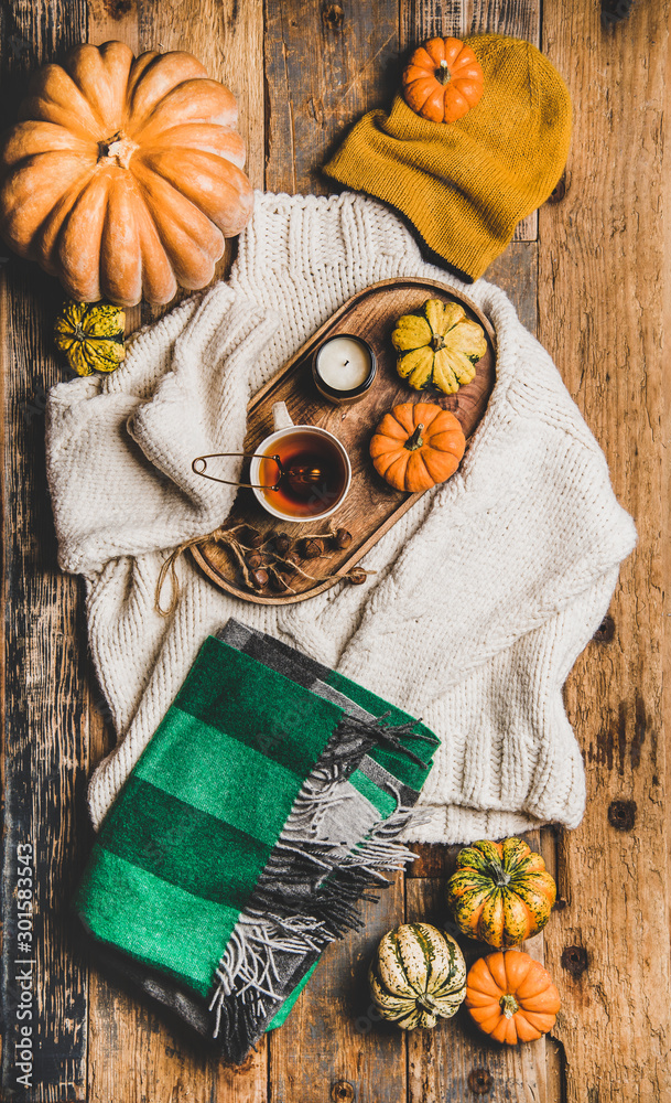 Autumn outfit layout. Flat-lay of beige knitted sweater, green woolen scarf, hat, decorative pumpkin