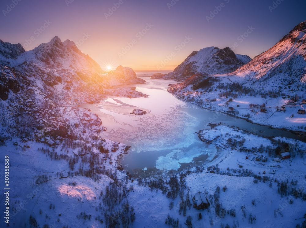 挪威罗弗敦群岛日落时的雪山、大海和紫色天空的鸟瞰图。冬季色彩