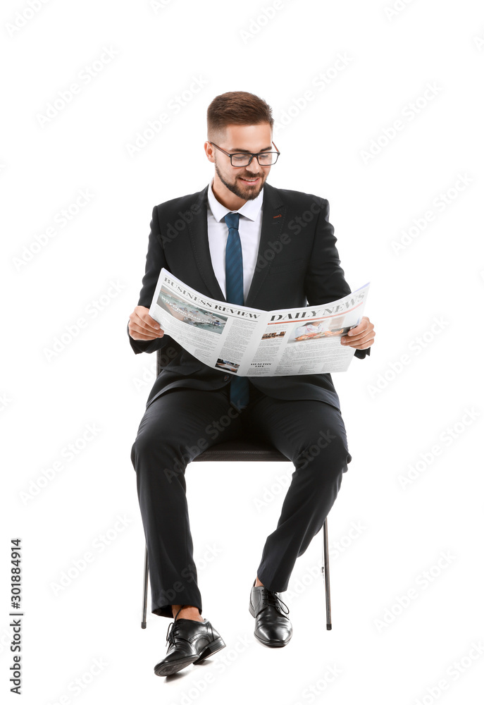 英俊的商人，拿着报纸坐在白色背景的椅子上
