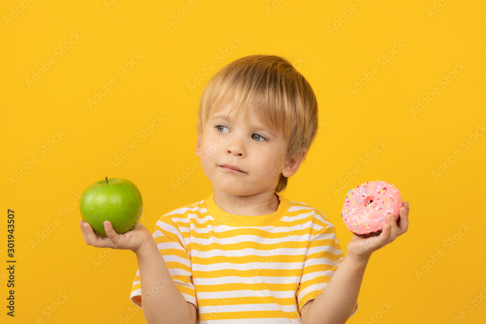 快乐的孩子拿着甜甜圈和苹果