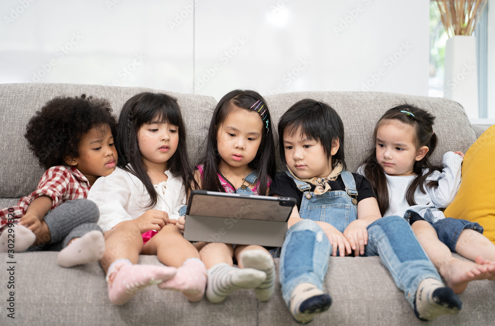 一群小孩子一起在数字平板电脑上看电影、电影和动画片。孩子们在玩t