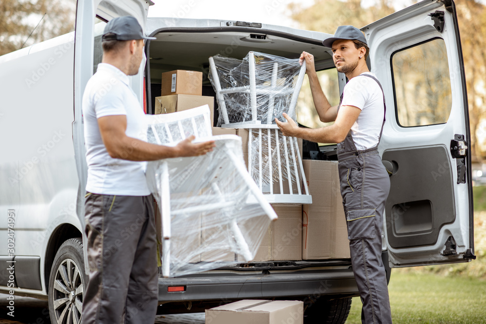 快递公司员工卸载货车，将一些货物和家具运送到cli