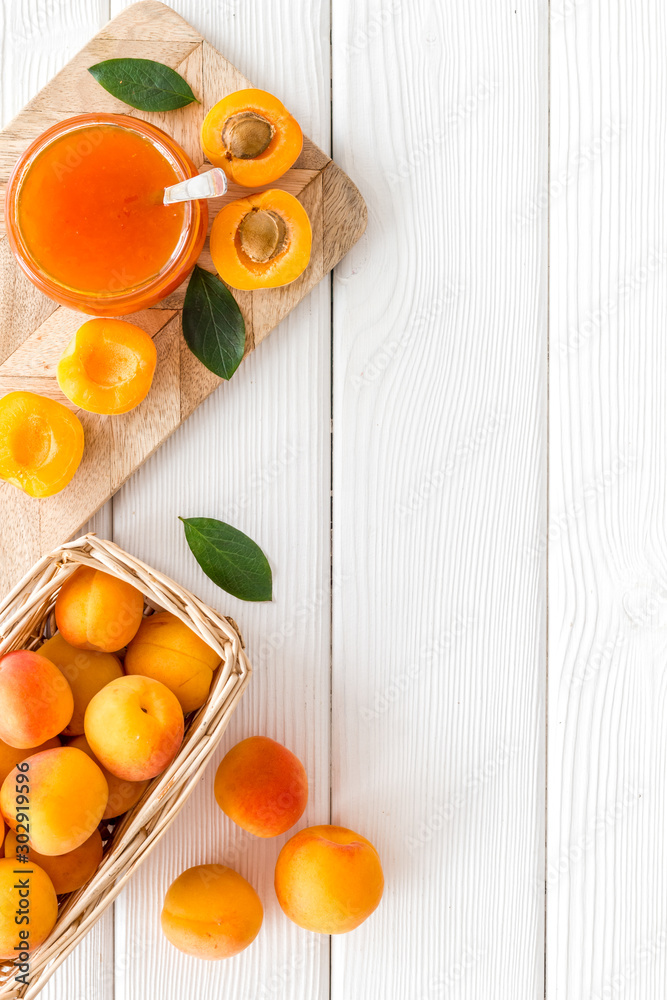 夏季蜜饯。白色木制背景俯视图上新鲜水果附近的罐子里的杏子酱。cop