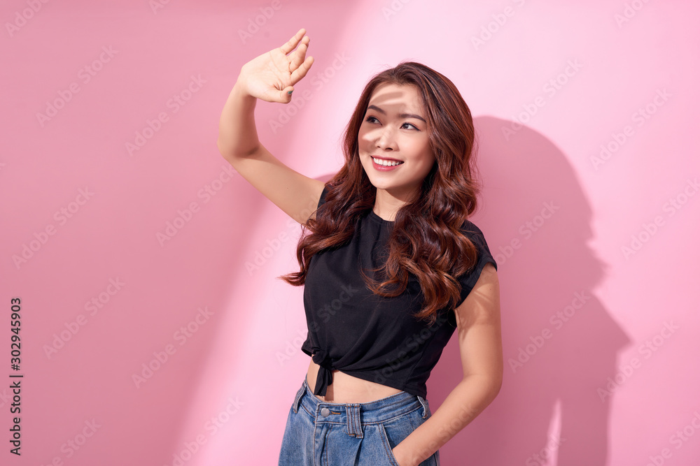 Young beautiful Asian woman scared of sunshine isolated over pink background. Concept for summer ski