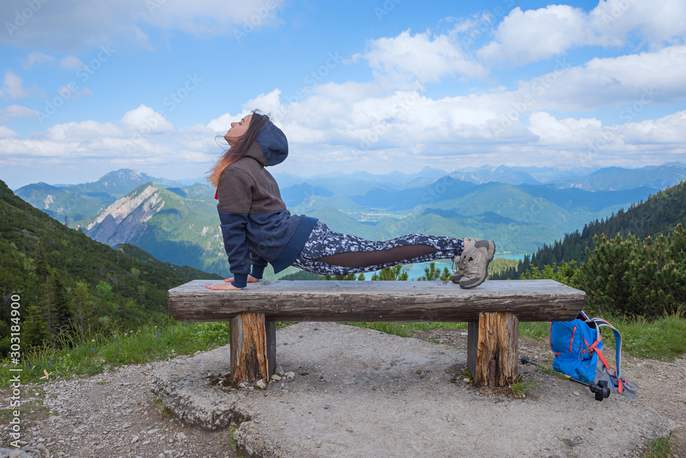 一名年轻女子在巴伐利亚阿尔卑斯山的木长椅上做运动