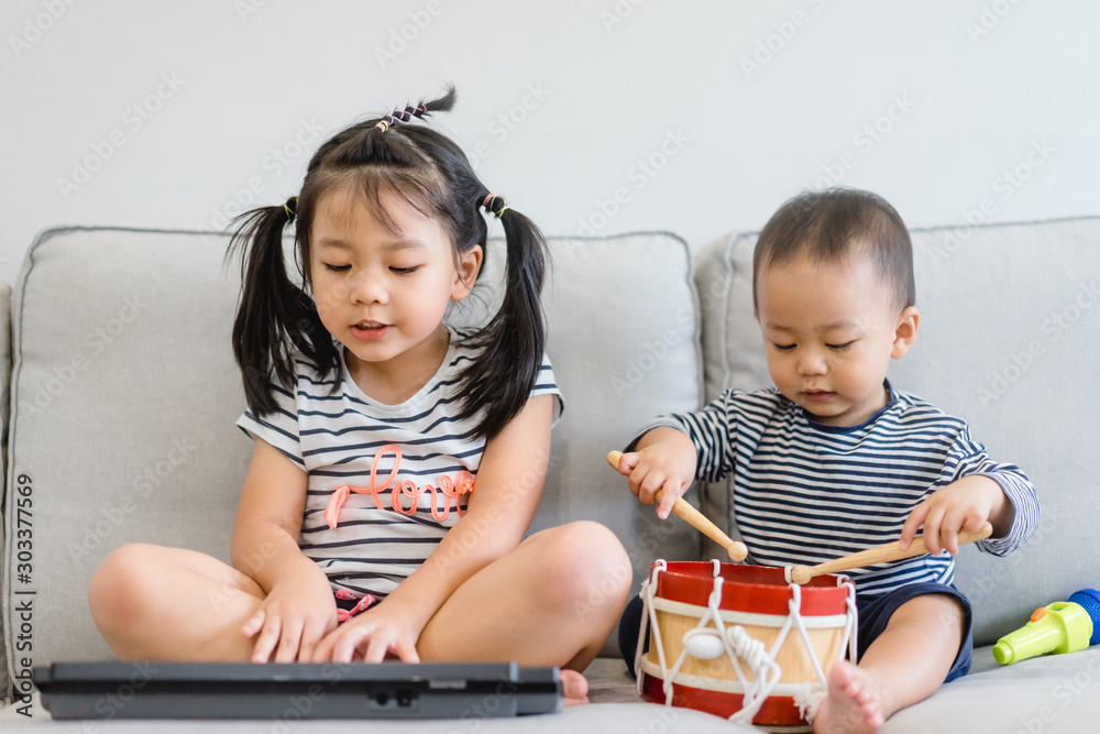 Little sister and her baby brother play with keyboard and drum and singing.Asian child playing and s