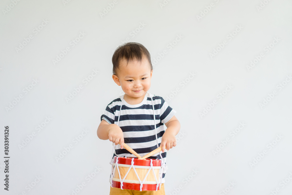 小男婴在家里打鼓。亚洲男孩在m里弹唱快乐时刻